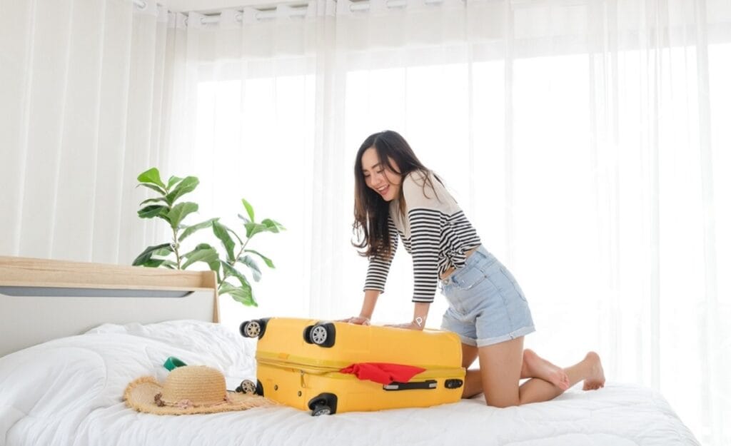 Mujer con dificultades para cerrar su maleta de fin de semana