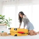Woman having difficulty closing her weekend suitcase