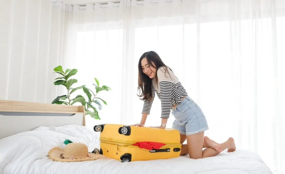 Femme ayant des difficultés pour fermer sa valise du weekend