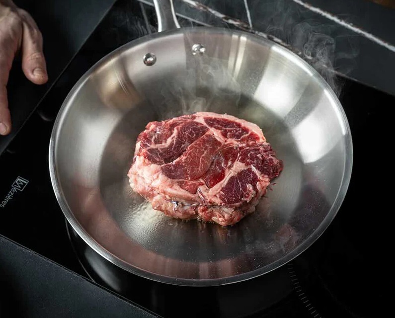 carne en una sartén de acero inoxidable