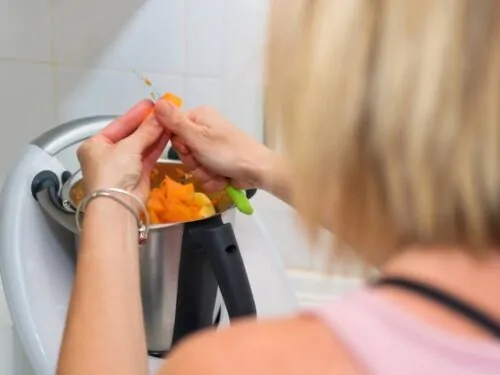 Mujer preparando una receta con un procesador de alimentos