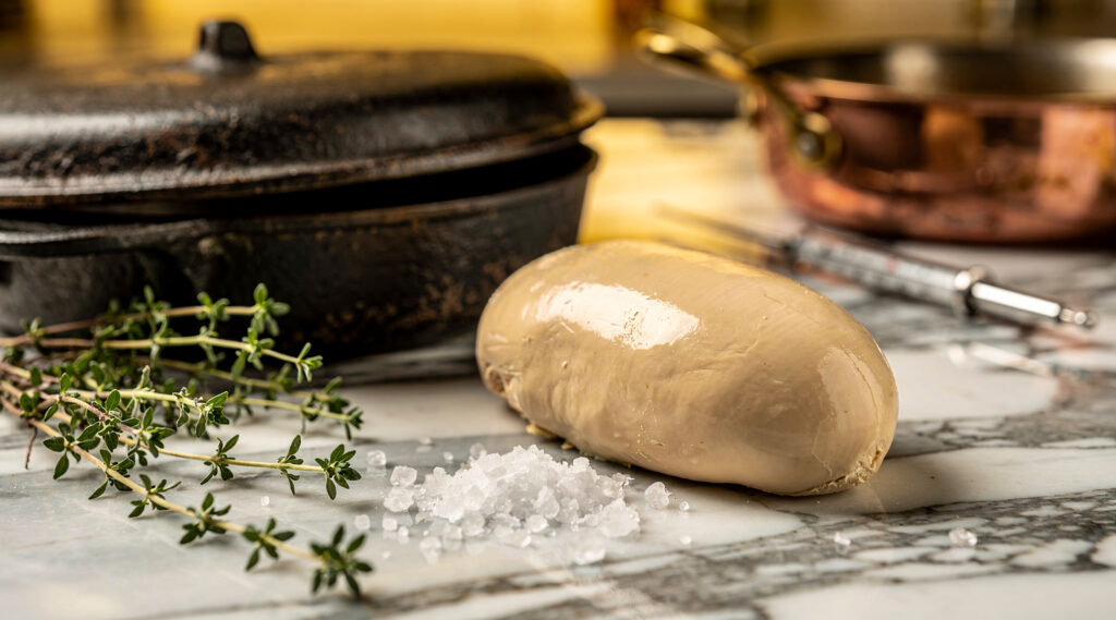Cocine un lóbulo de foie gras crudo sobre una losa de mármol rodeada de tomillo fresco y sal marina