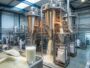Lait en poudre dans une cuillère métallique devant des tours de séchage industrielles