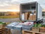 Camion frigorifique de livraison alimentaire avec colis isothermes et produits frais en premier plan