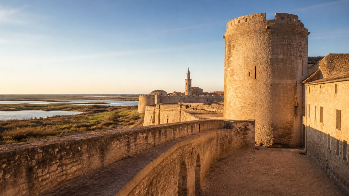 Étape à Aigues-Mortes sur l'itinéraire du road trip en Camargue Remparts médiévaux d'une cité fortifiée en Camargue avec les marais salants en arrière-plan