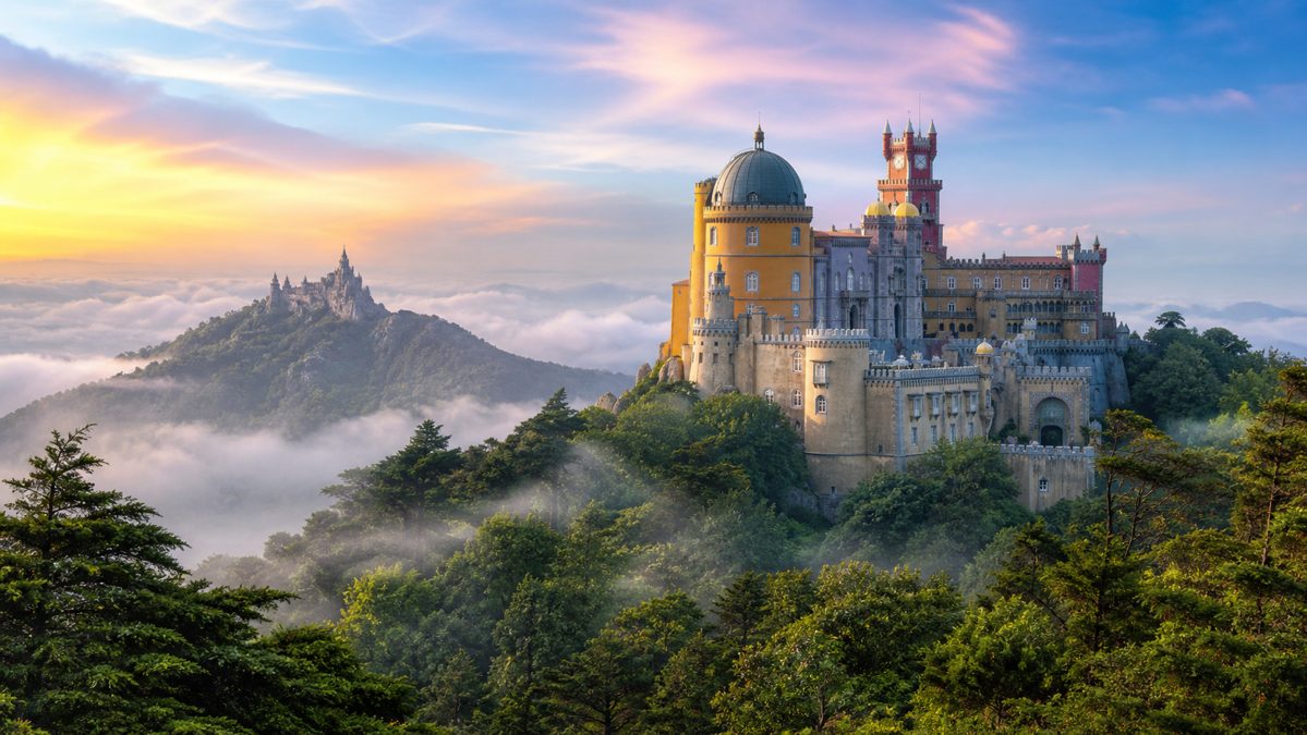 Le palais coloré de Sintra sur sa colline Palais romantique aux tours colorées sur une colline boisée avec un château visible au loin dans la brume
