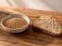 Grains de petit épeautre crus et tranche de pain au levain sur table en bois