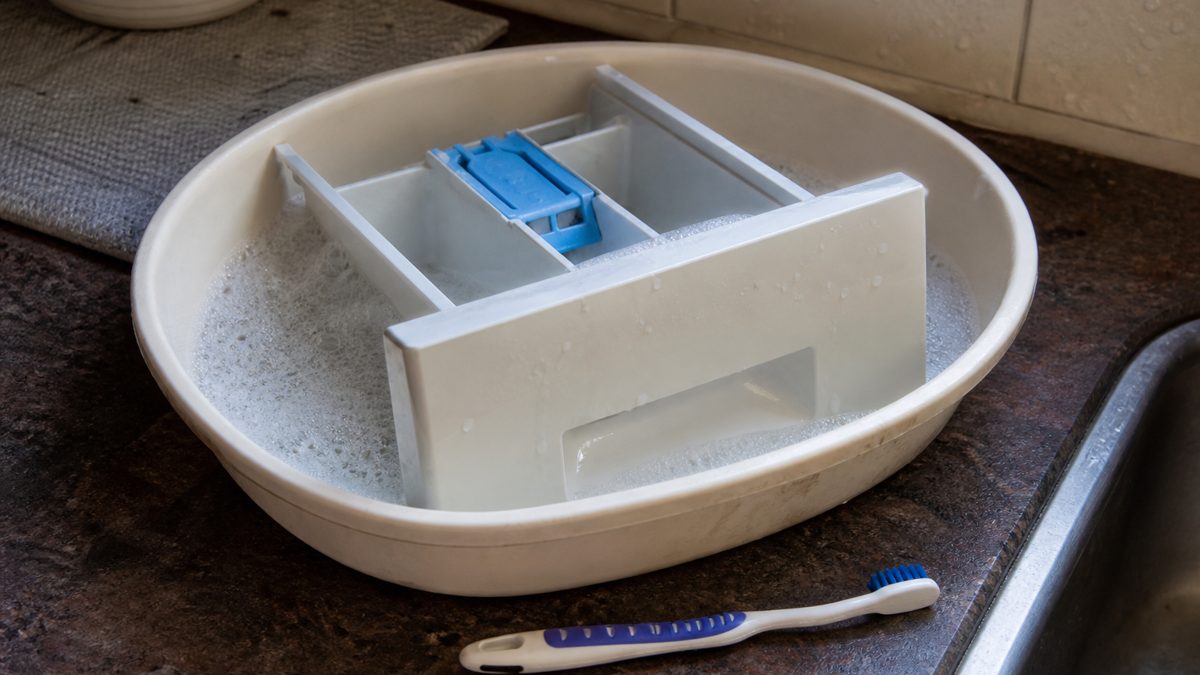 Nettoyer machine à laver : diagnostic par symptôme Bac à lessive retiré de la machine et trempé dans l'eau chaude savonneuse