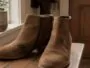 Bottines en daim posées sur un banc d'entrée avec une tache visible à traiter