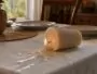 Bougie renversée laissant une coulure de cire fraîche sur une nappe en coton