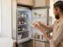 Personne essuyant l'intérieur d'un réfrigérateur ouvert dans une cuisine lumineuse