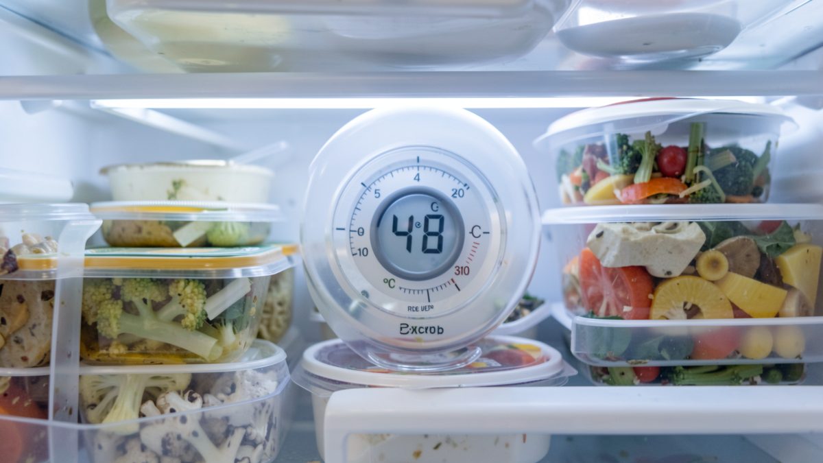 Température du frigo et fréquence de nettoyage idéale Thermomètre de frigo affichant une température proche de 4 degrés parmi des aliments rangés