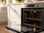 Puerta del horno abierta con una ventana perfectamente limpia en una cocina luminosa