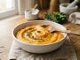 Bol de purée orange onctueuse de carottes et pommes de terre posé sur une table en bois